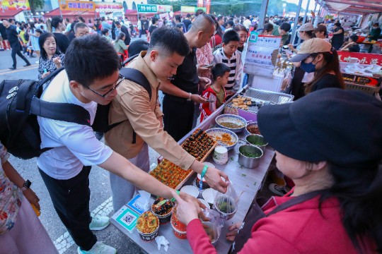 图为游客在大厂美食节品尝美食。何赛摄。.JPG